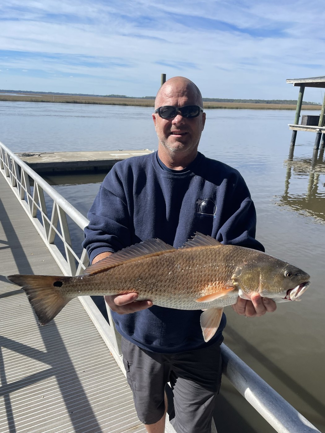 Angler holding a redfish beside a dock rail