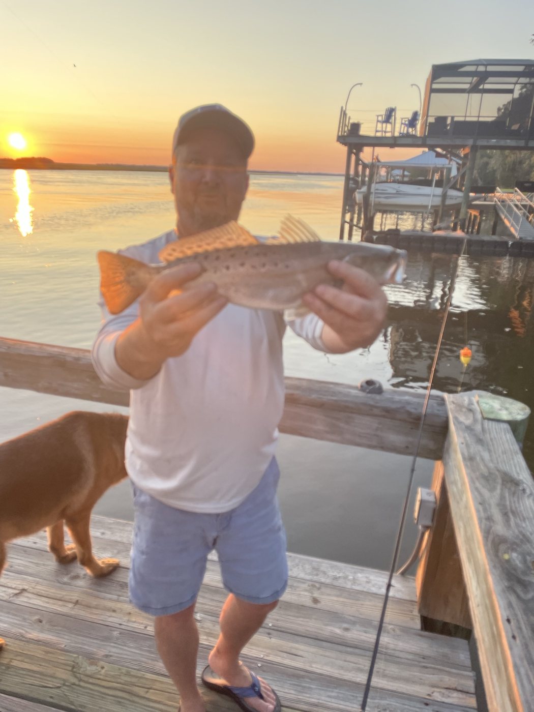 Angler holding a fish on the dock at sunset